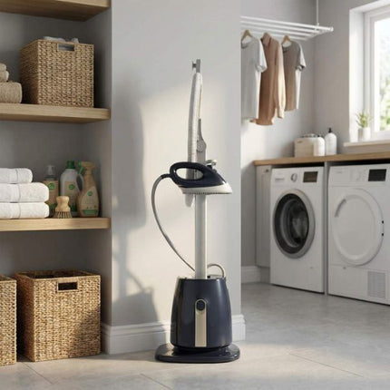 A steam iron and steam cleaner set standing on a tiled floor in a bright laundry room. The set includes a dark navy base, a silver vertical steam tube, and a black-and-silver steam iron hanging from a loop on the side.