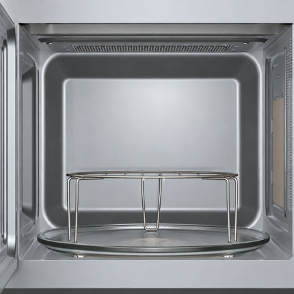Interior of the Bosch Series 2 microwave showing a glass turntable, raised metal wire rack and perforated upper panel.