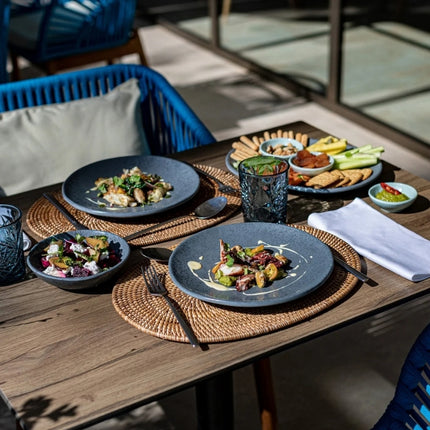 Dalebrook Mineral Agate grey melamine plates serving plated salads on woven placemats at a restaurant table.