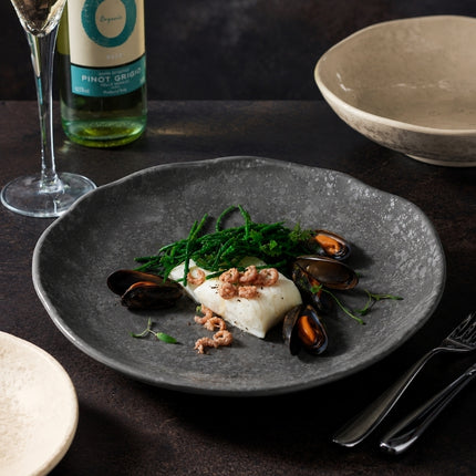 Dalebrook Mineral Agate grey plate serving white fish, mussels and green vegetables beside a glass of white wine.