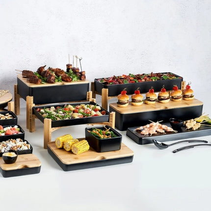 Wide buffet display using Dalebrook Nimble stands, black serving trays and bamboo boards at multiple heights.