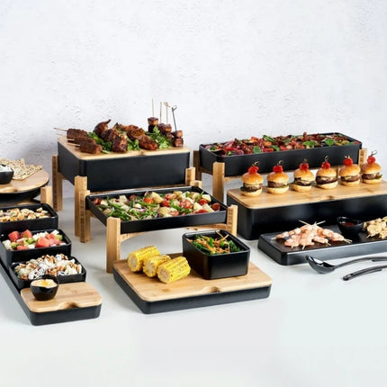 Tiered catering display featuring Dalebrook Nimble buffet stands, black serving trays and bamboo boards filled with assorted food.