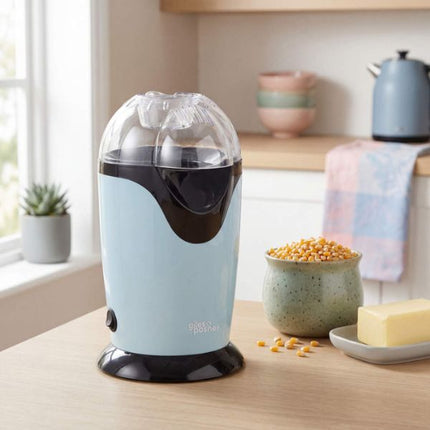 Blue and black popcorn maker on a kitchen counter with a bowl of popcorn kernels and a stick of butter.
