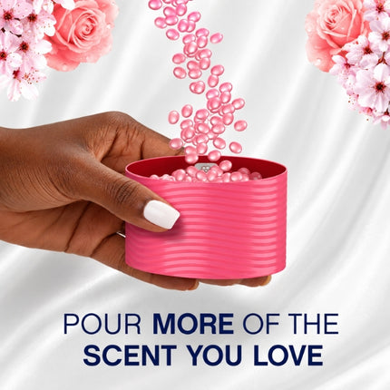 Pink Lenor scent booster beads pouring into a measuring cap held by hand, with the message “Pour more of the scent you love.”
