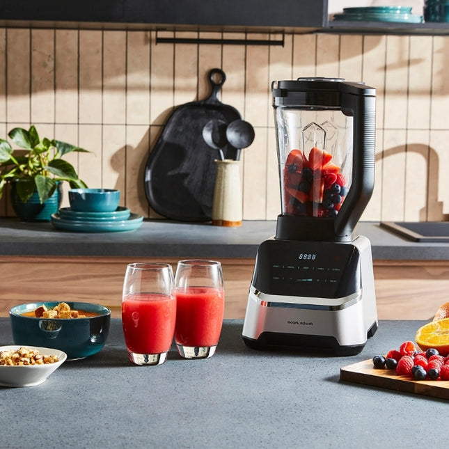 Morphy Richards jug blender filled with mixed berries on a kitchen counter beside two glasses of red smoothie.