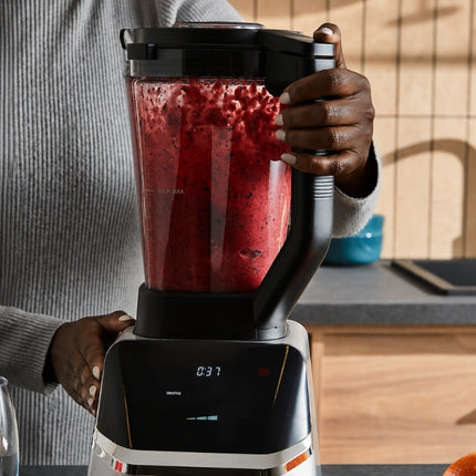 Morphy Richards blender mixing berries into a smooth red drink while a person holds the jug handle.