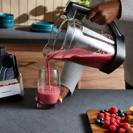 Person pouring a freshly blended berry smoothie from the Morphy Richards blender jug into a glass.