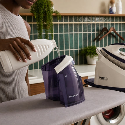 Woman pouring water into the removable purple tank of the Morphy Richards Speed Steam generator iron.