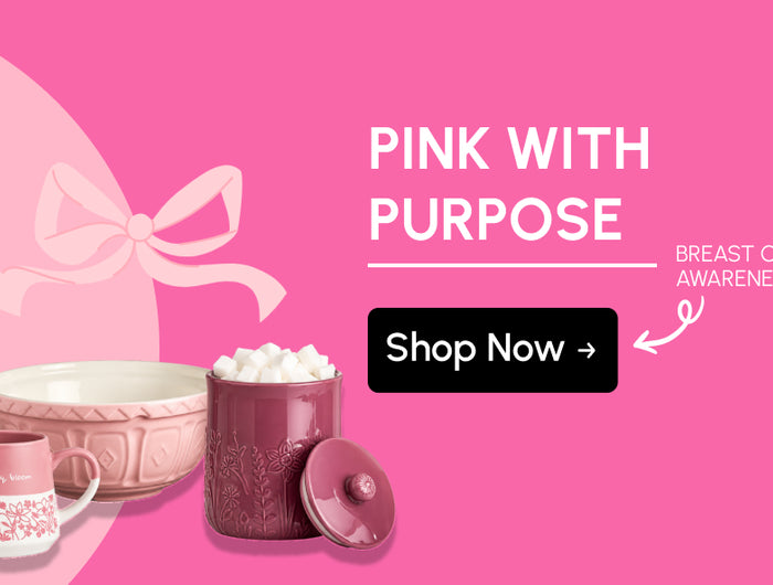 Pink With Purpose Breast Cancer Awareness banner featuring coordinated pink kitchenware, including a floral mug, ceramic mixing bowl and embossed storage canister, alongside a pink awareness ribbon and Shop Now call to action.