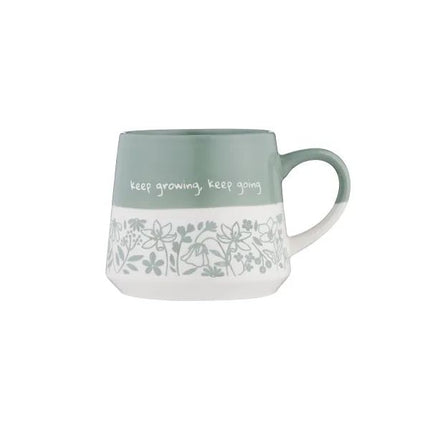 A ceramic mug with a sage green upper half, white lower half, and a delicate floral line-art pattern around the middle. The mug features the handwritten text 'keep growing, keep going' on the green section and has a matching sage green handle.