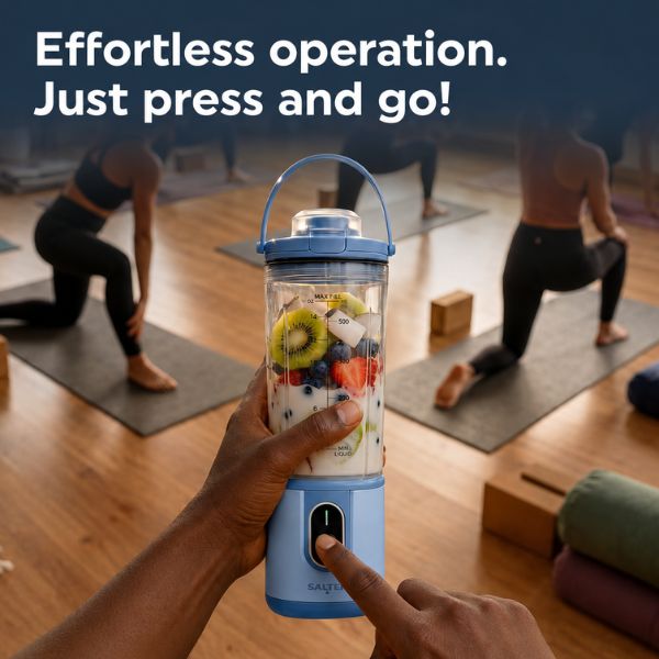 A light blue portable blender bottle with a clear cup filled with fruit and yogurt is held up in a yoga studio, with people practicing in the background and the text 'Effortless operation. Just press and go!' at the top.