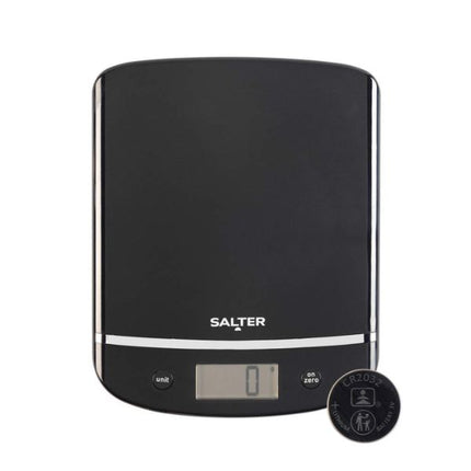 A Salter digital kitchen scale with a black weighing platform, silver trim, and a small LCD display showing '0'. A round black accessory or cover is placed in front of the scale on a plain white background.