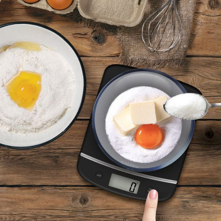 Baking ingredients on a digital kitchen scale with flour, butter, and an egg on a wooden surface.