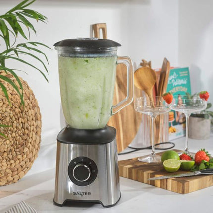 Salter blender with a green smoothie on a kitchen counter, surrounded by fruits and kitchen utensils.