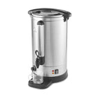 A stainless steel commercial coffee or tea dispenser with black plastic lid, handle, and base components, shown on a plain white background with a clear glass cup placed on the drip tray.