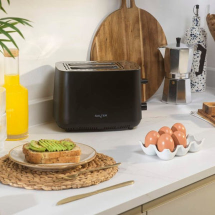 Black toaster on a kitchen counter with toast, avocado, and eggs.