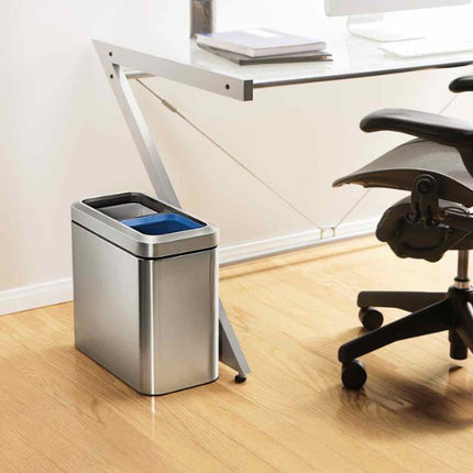 Simplehuman 20L Slim Open Recycler Bin in brushed steel beside an office desk and chair, showing its compact space-saving design.
