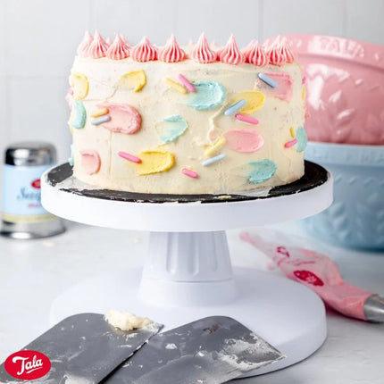 Tala 12.5 cm stainless steel icing scraper beside a pastel-decorated buttercream cake on a cake stand