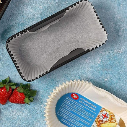 Tala siliconised 1 lb loaf liner fitted inside a black loaf tin, with extra liners and strawberries nearby