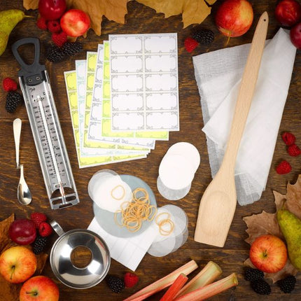 Tala jam thermometer arranged with a wooden spoon, jar labels, covers and fresh fruit for homemade jam making