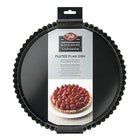 A black fluted round tart pan in its retail packaging, featuring a hanging cardboard header with the Tala brand logo and a label identifying it as a fluted flan dish.