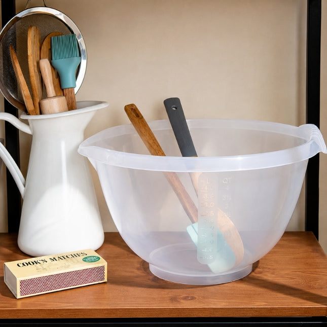 Wham Cuisine 7L clear mixing bowl with measurement markings, holding wooden spoons and spatulas, and a match box on a kitchen shelf.